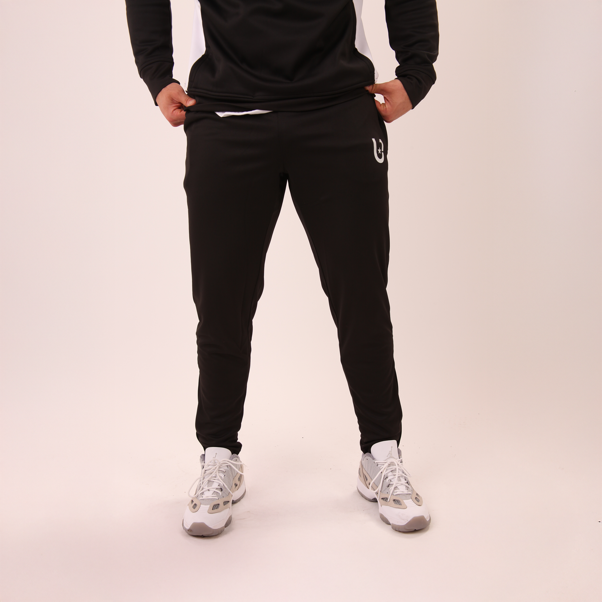 front view of UNIFY black athletic track pants for men with clean, tapered fit