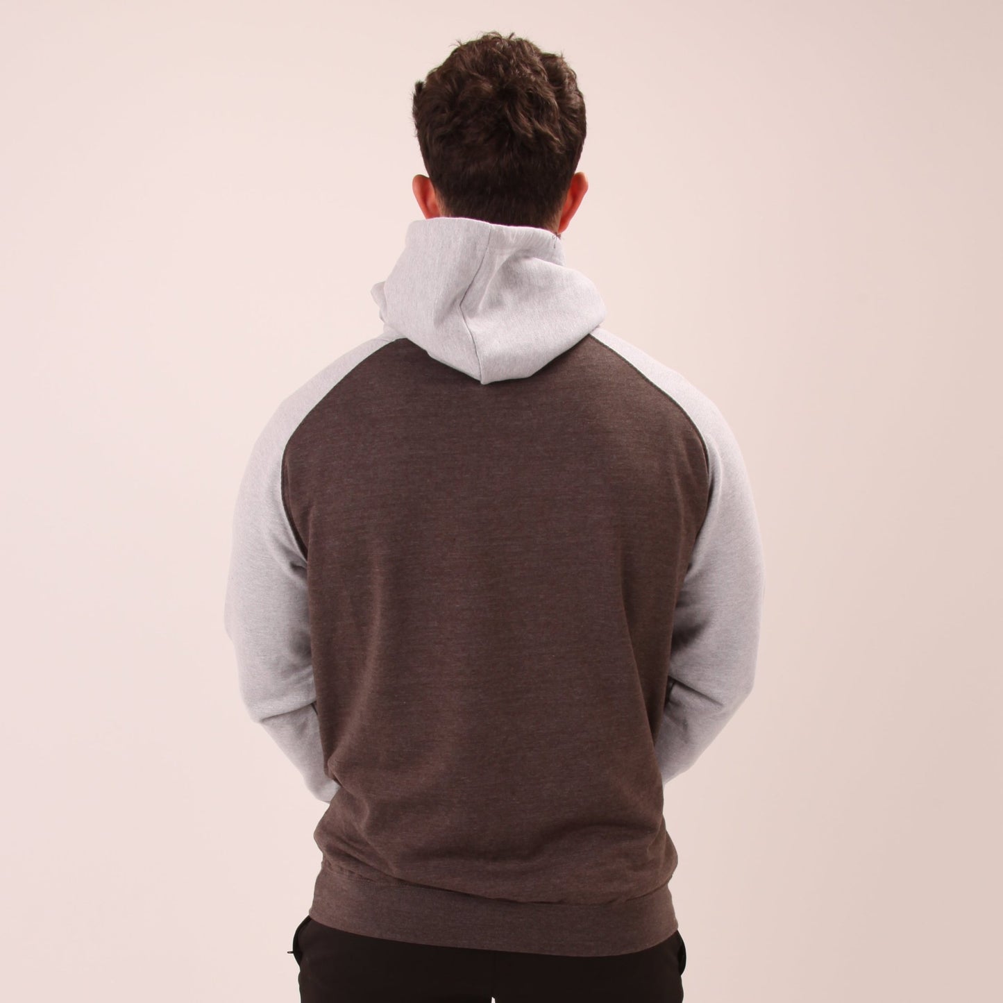 "A man lounges in a UNIFY grey hoodie, showcasing its versatile and stylish design."