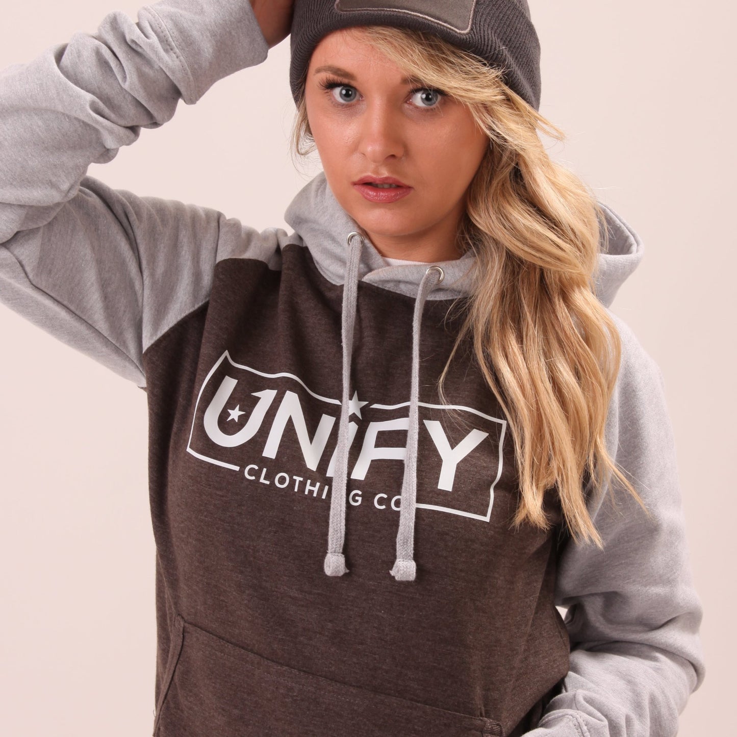 "UNIFY's women's grey hoodie, modelled in an urban environment, showcasing practicality and chic design."