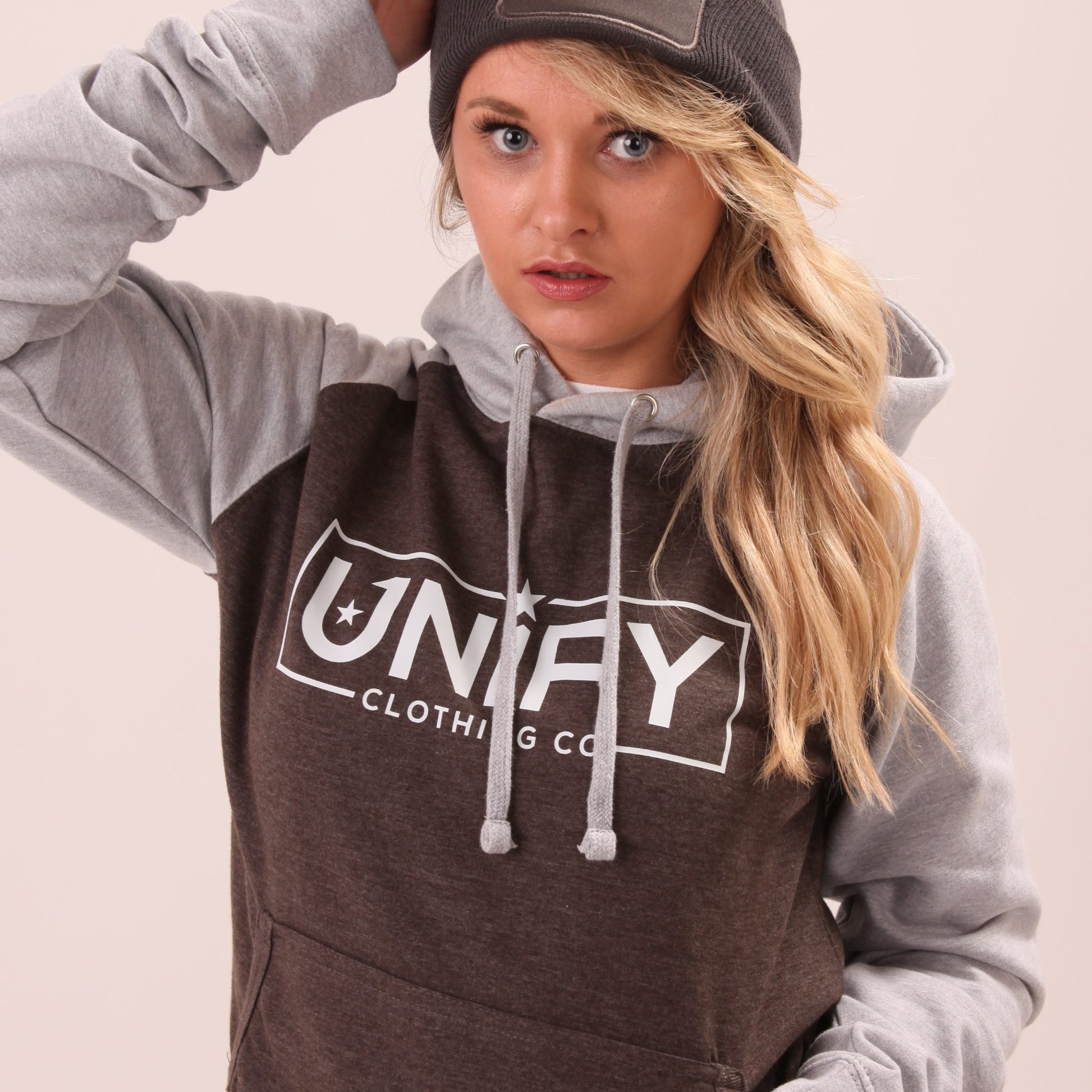 "UNIFY's women's grey hoodie, modelled in an urban environment, showcasing practicality and chic design."