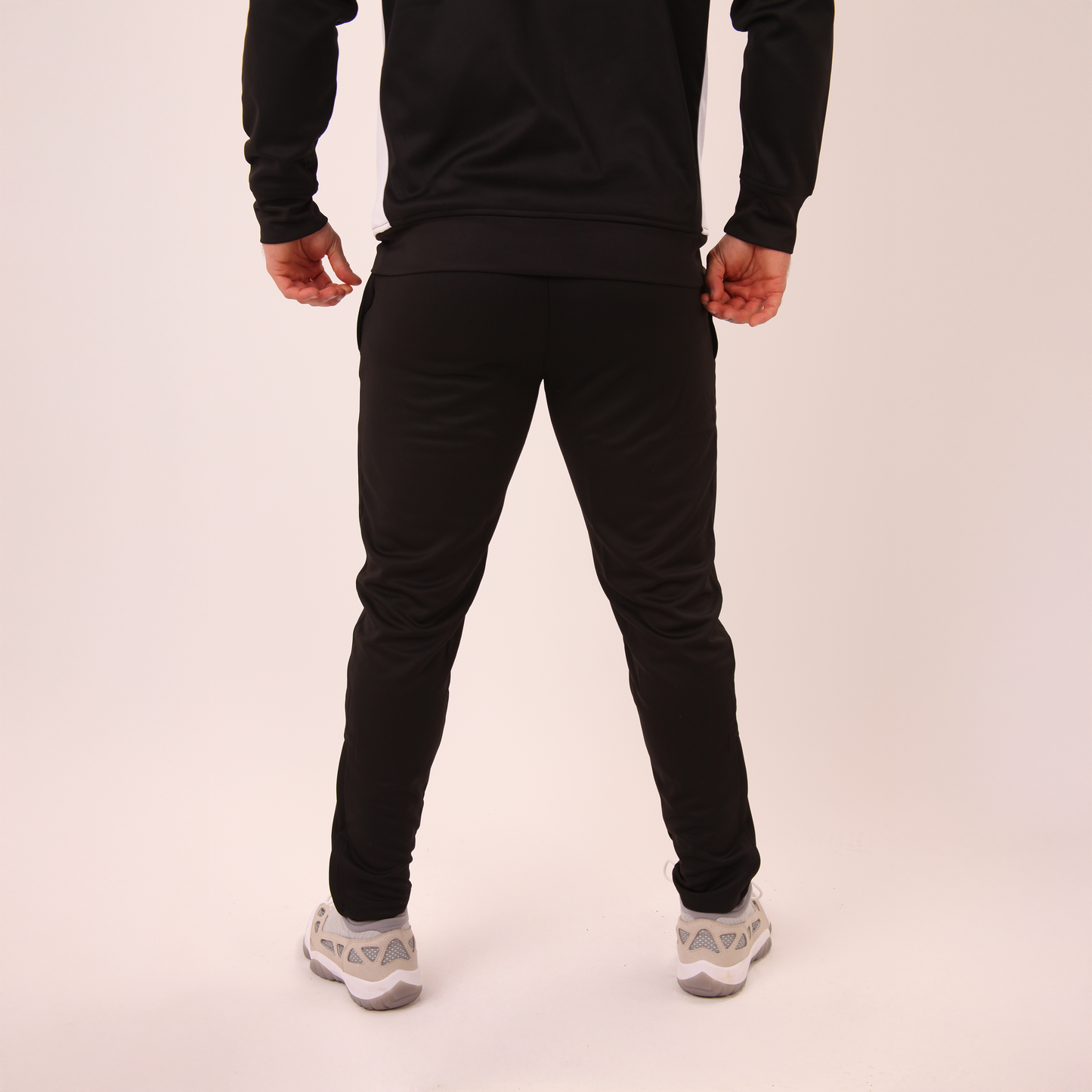 back view of men's UNIFY black track pants showing smooth fabric and streamlined cut