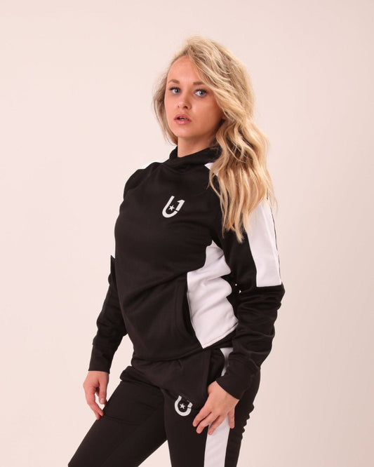 "UNIFY Women's black track pants with white stripes, displayed in a gym setting for a sporty look."