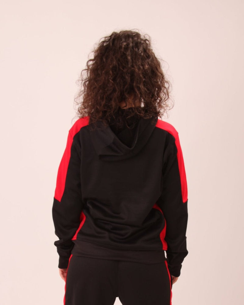 "UNIFY Women's Black/Red Crossover Track Pants worn in an urban environment, highlighting their versatility."