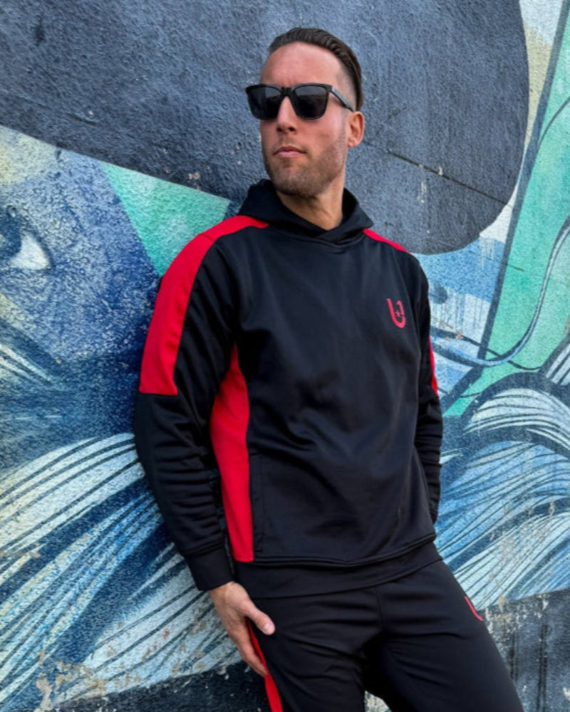 "Man standing casually in UNIFY track pants, showcasing their comfort and stylish design in an urban setting."