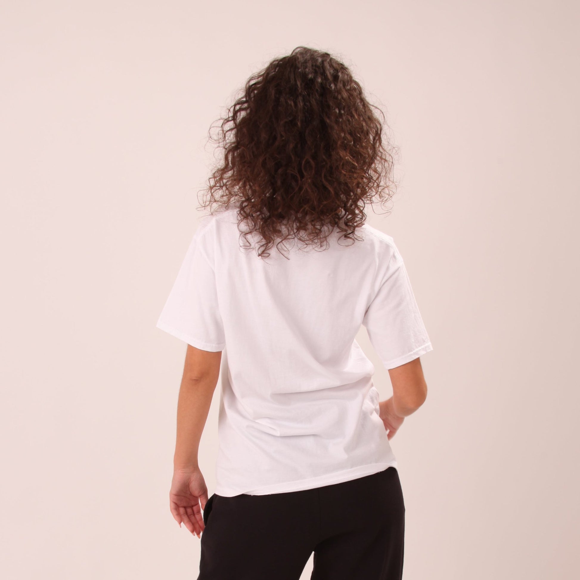 "UNIFY women's white t-shirt laid flat on a wooden background, emphasizing simplicity and quality."
