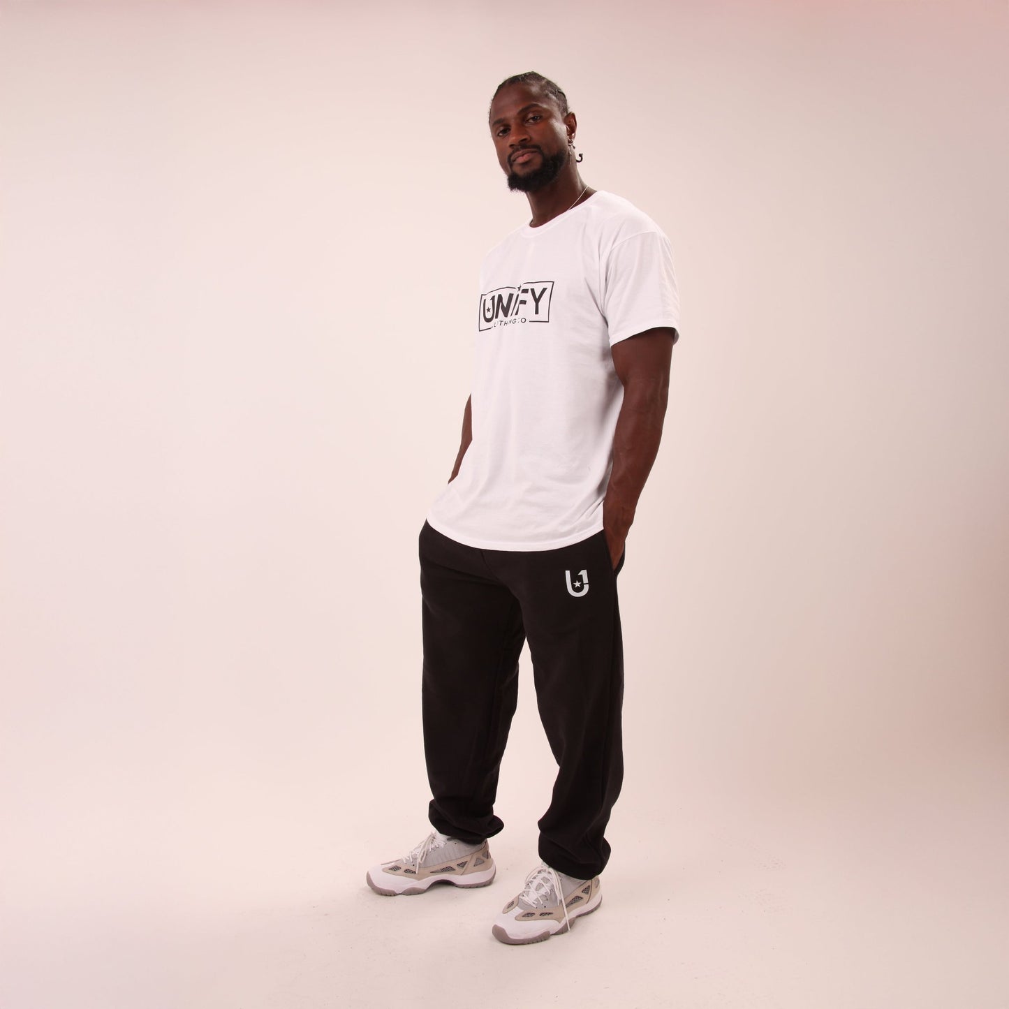 Pair of UNIFY men's relaxed black joggers laid out, showcasing the loose fit and sleek black colour.