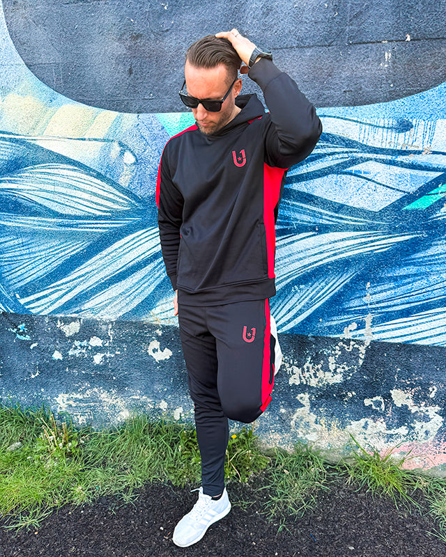 Side angle of black and red stripe track suit showcasing athletic fit