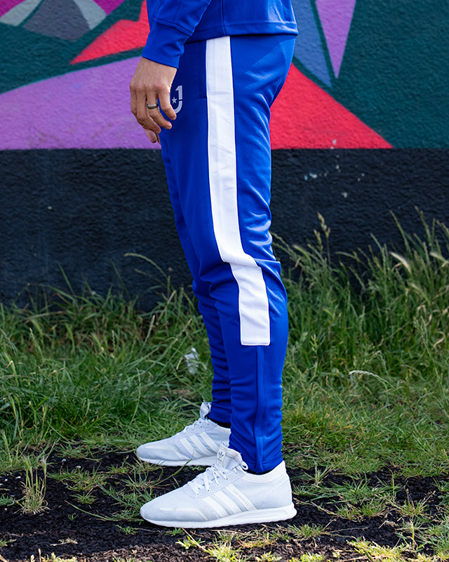 Blue track pants showing side stripe design and slim fit