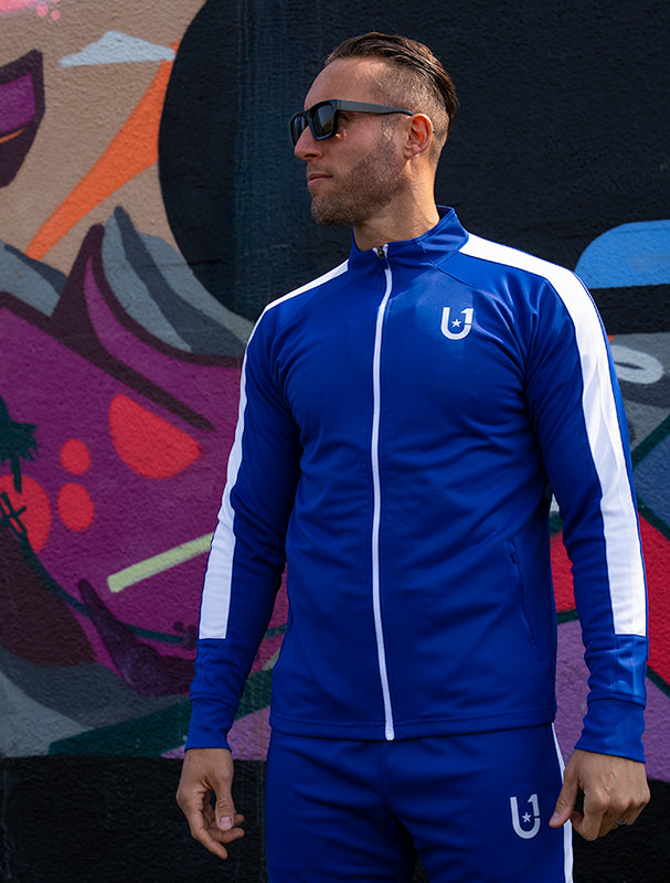 Side profile of the UNIFY blue and white track top with stripe accents