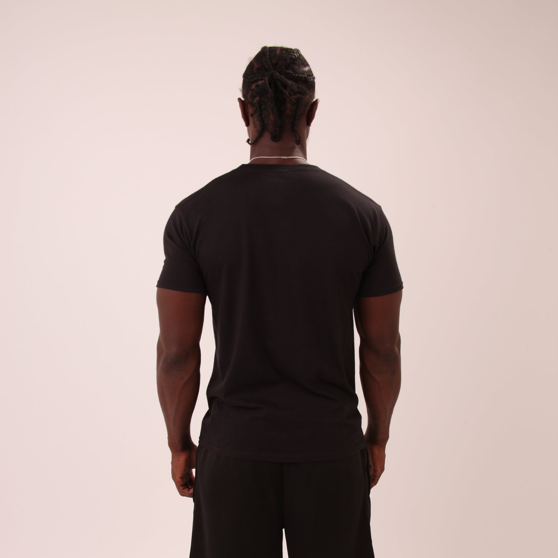 "Fashionable young man wearing UNIFY Men’s Black T-Shirt in an urban setting, showcasing its versatility."

