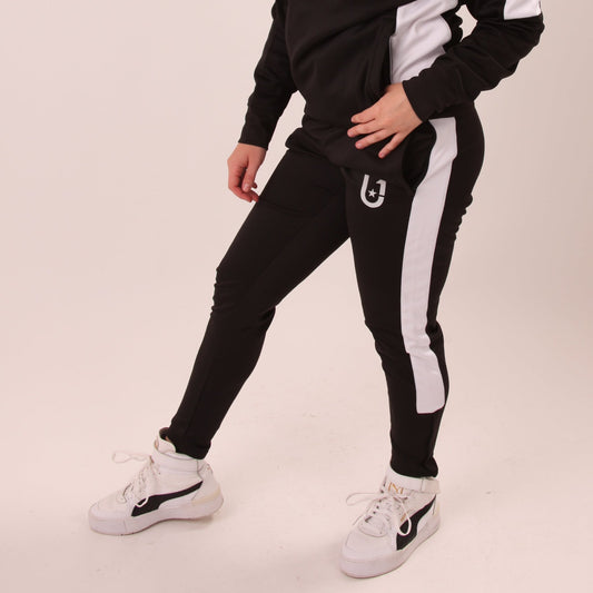 "UNIFY women's track pants in black with white accents, blending fitness wear with contemporary fashion."
