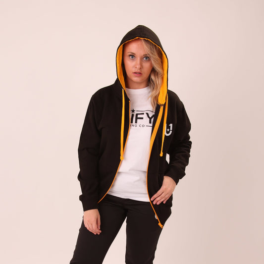 Woman sporting a black and yellow UNIFY zip hoodie, blending casual style with athletic comfort.
