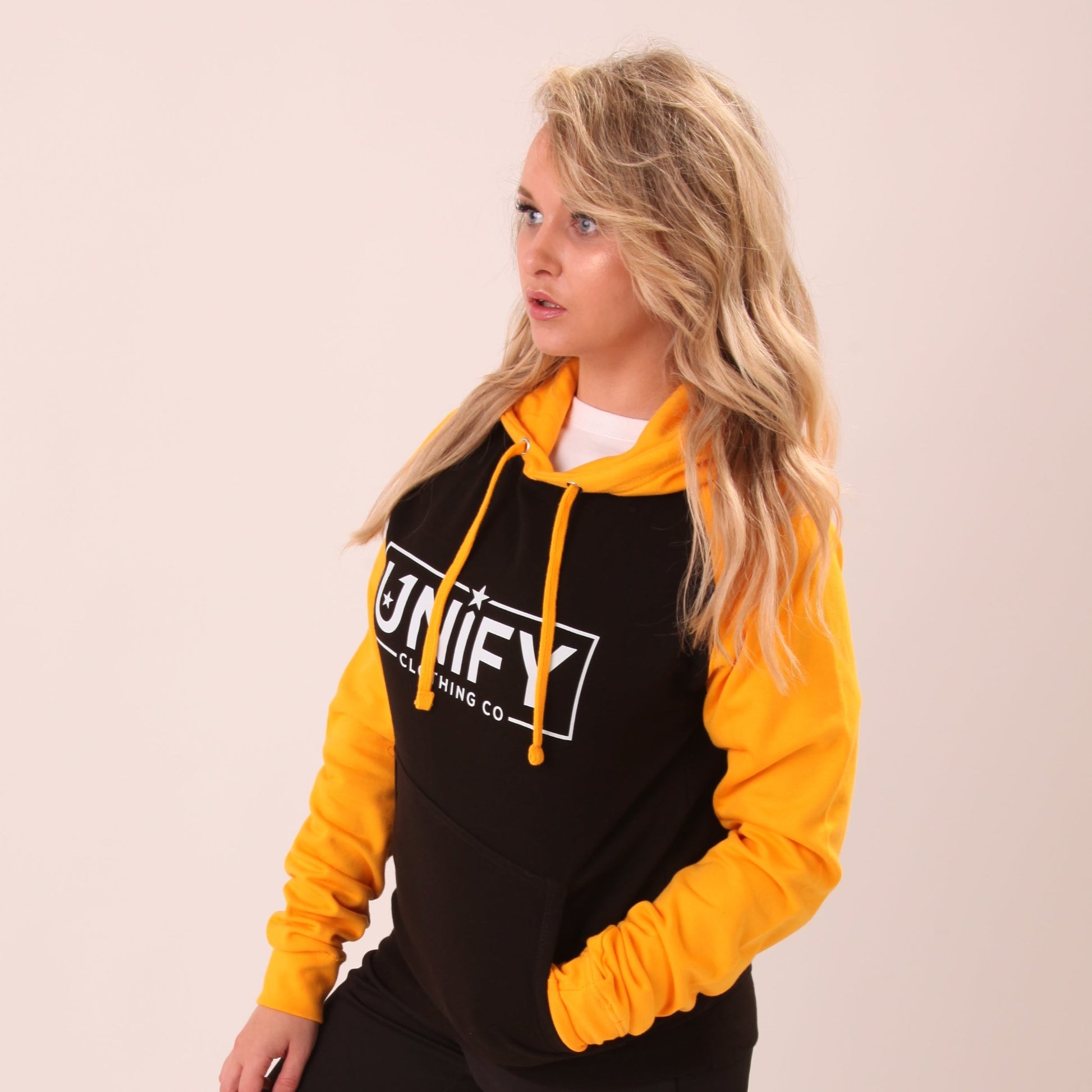 "Woman sporting the UNIFY yellow jumper, showcasing its soft texture and comfy fit."
