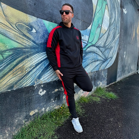 "Man standing casually in UNIFY track pants, showcasing their comfort and stylish design in an urban setting."