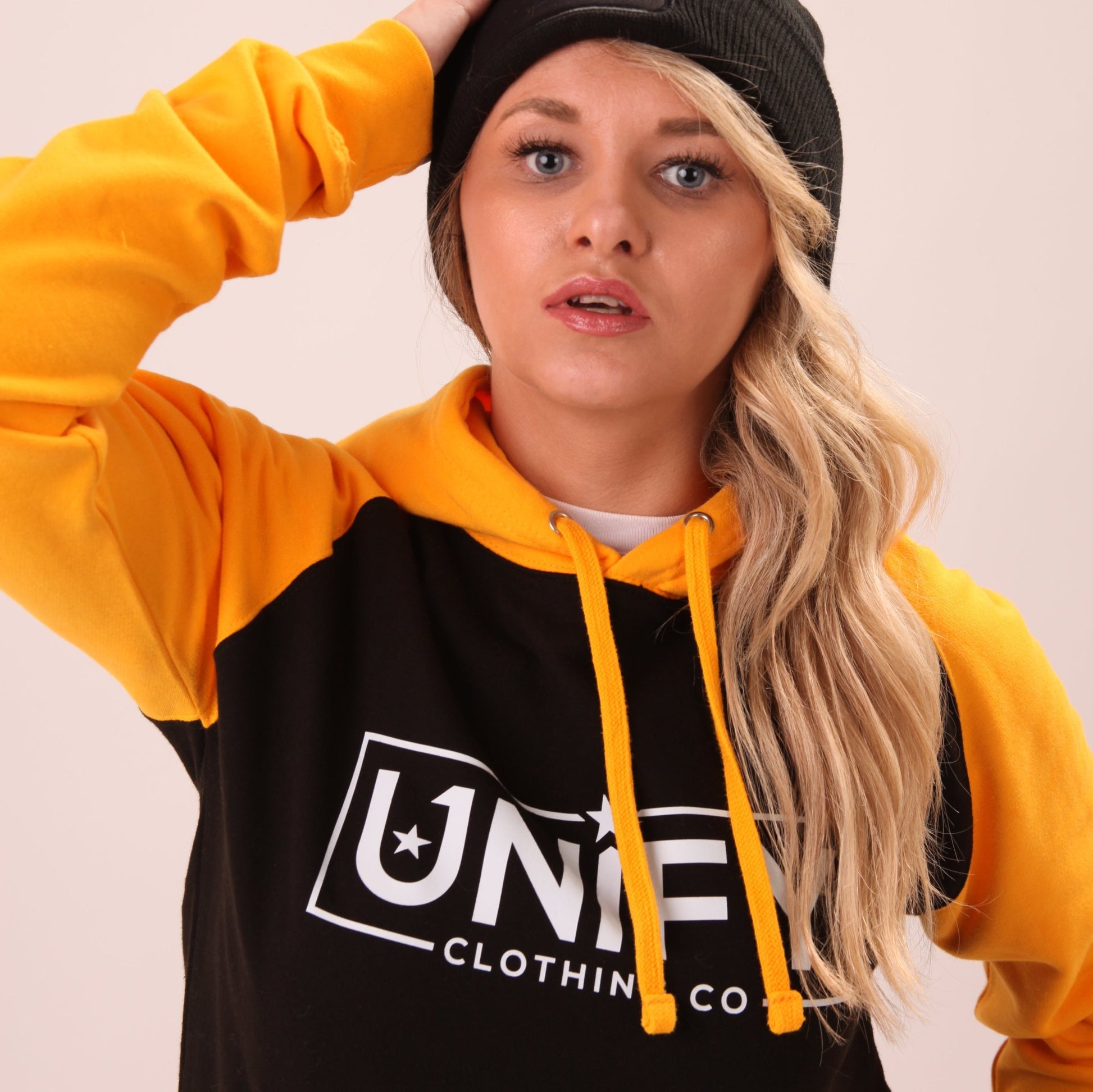 "Fashionable and functional UNIFY women's hoodie in sunny yellow, worn by a model in a relaxed setting."
