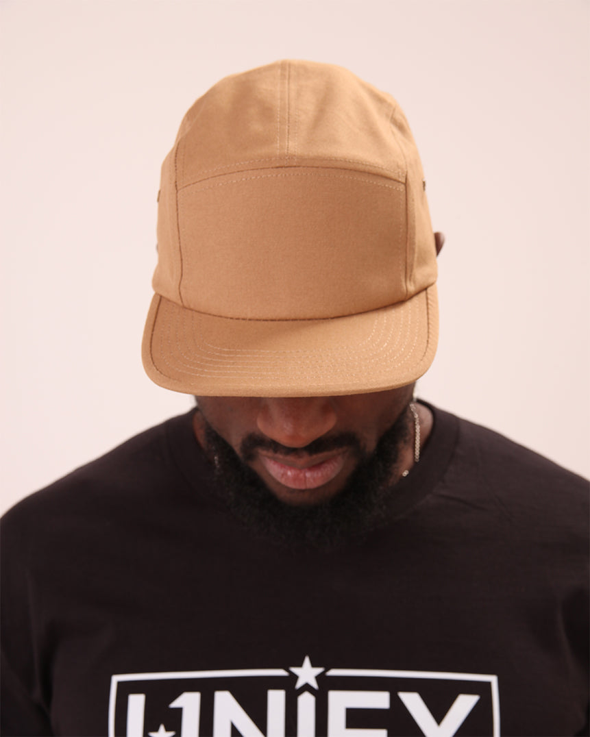 Close-up of the UNIFY beige streetwear cap showing its fine craftsmanship and neutral hue.