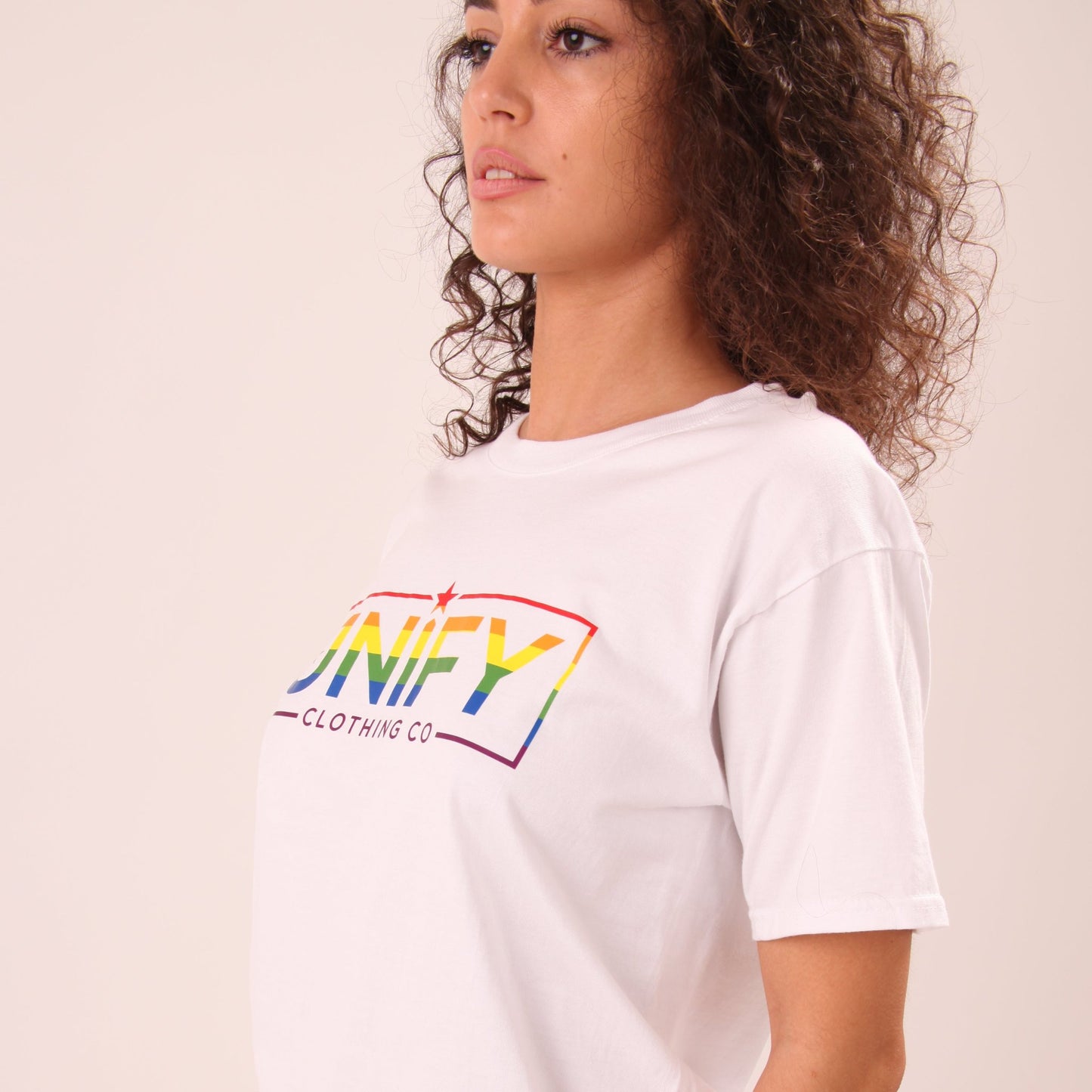 "Woman wearing a vibrant Pride tee, showcasing bold rainbow stripes for visibility and pride."
